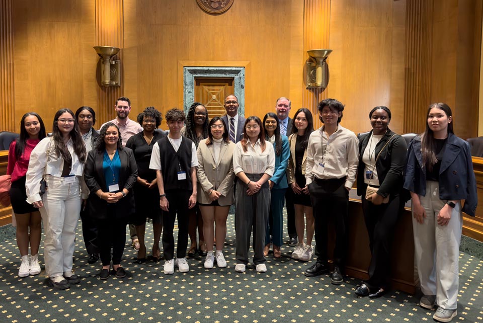 Students pose for a photo in the U.S. senate, standing in two rows and looking at the camera.
